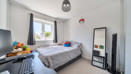 Bedroom with bed, desk, large mirror and neutral décor
