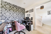 Home office with desk, chair, patterned feature wall and light carpet