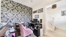 Home office with desk, chair, patterned feature wall and light carpet