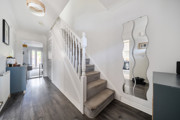 Hallway with staircase, wall mirror, and wood-effect flooring.