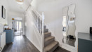 Hallway with staircase, wall mirror, and wood-effect flooring.