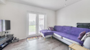 Living room with a purple sofa, TV and patio doors to the garden.