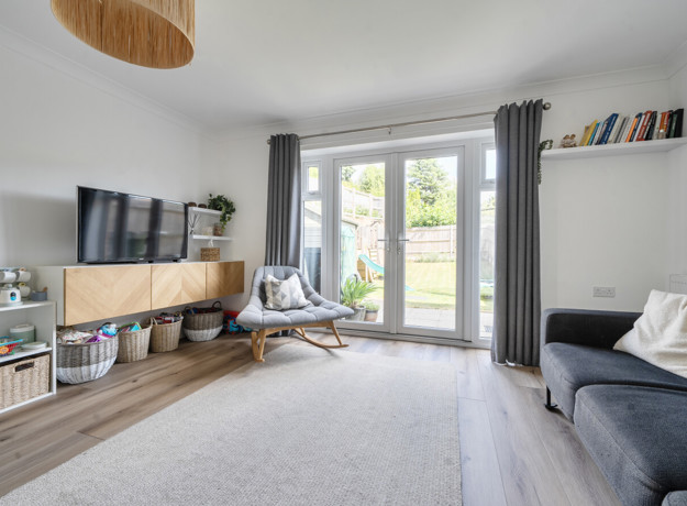 Living room with shelving, seating and patio doors to the garden.