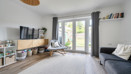 Living room with shelving, seating and patio doors to the garden.