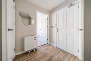 Entrance hallway with white doors, radiator and wall mirror.