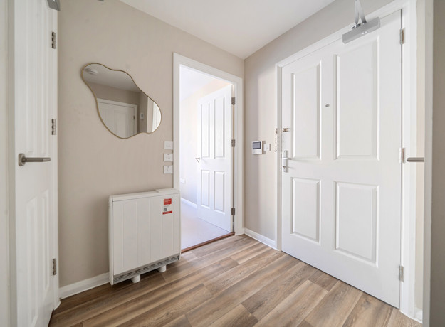 Entrance hallway with white doors, radiator and wall mirror.
