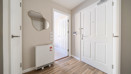 Entrance hallway with white doors, radiator and wall mirror.