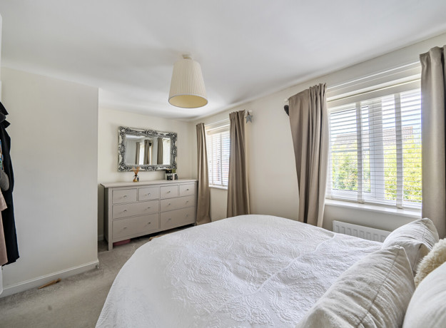 Bedroom with a bed, chest of drawers, mirror and window.