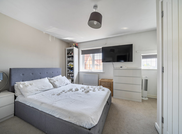 Spacious bedroom with double bed, wall-mounted TV, and neutral decor.