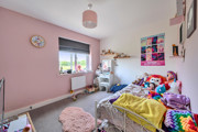 Children's bedroom with single bed, shelving, window and pink wall.