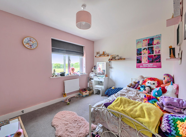 Children's bedroom with single bed, shelving, window and pink wall.