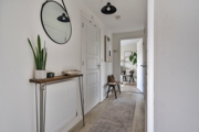 Hallway with console table, mirror, plant, and open doorway to living space.