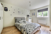 Bedroom with patterned bedding, window, radiator and light walls.