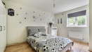 Bedroom with patterned bedding, window, radiator and light walls.