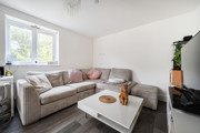 Living room with sofas, coffee table, TV and window overlooking the exterior.
