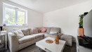 Living room with sofas, coffee table, TV and window overlooking the exterior.