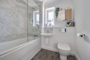 Bathroom with a bath, toilet, sink and glass shower screen.
