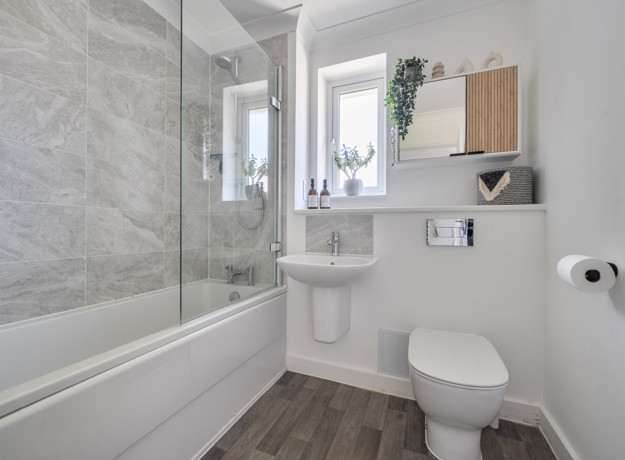 Bathroom with a bath, toilet, sink and glass shower screen.