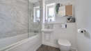 Bathroom with a bath, toilet, sink and glass shower screen.