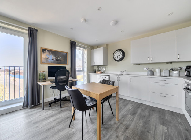 Kitchen and dining area with table, chairs, cabinets, and appliances.