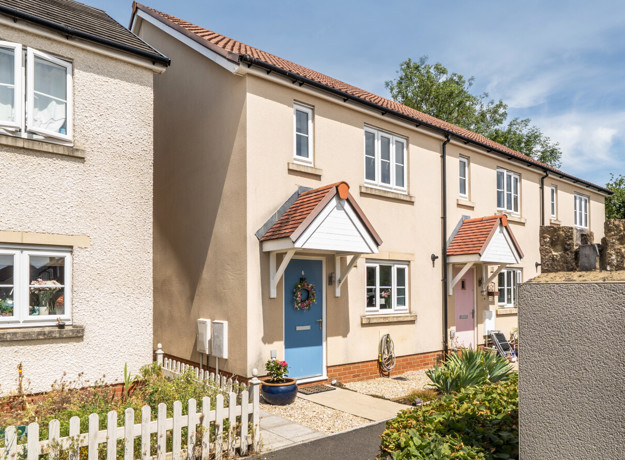 Terraced houses with front gardens, driveways, and paved walkway.