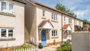 Terraced houses with front gardens, driveways, and paved walkway.