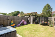 Garden with grass lawn, patio seating, play area, and shed.