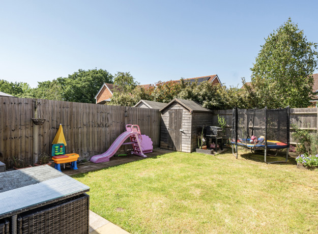 Garden with grass lawn, patio seating, play area, and shed.