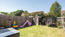 Garden with grass lawn, patio seating, play area, and shed.