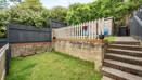 Terraced back garden with grass lawn, steps, retaining wall and shed.