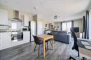 Open-plan kitchen and living area with dining table and sofas.