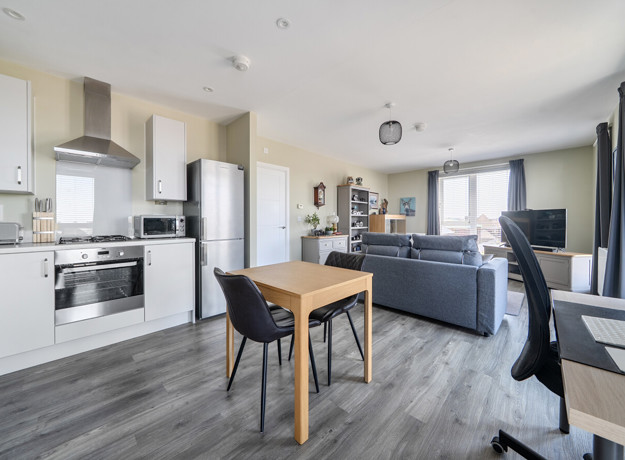 Open-plan kitchen and living area with dining table and sofas.