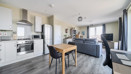 Open-plan kitchen and living area with dining table and sofas.