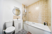 Bathroom with tiled walls, bathtub with shower, toilet and vanity unit
