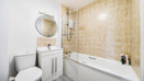 Bathroom with tiled walls, bathtub with shower, toilet and vanity unit