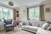 Living room with sofa, armchair, window and toys on shelves.