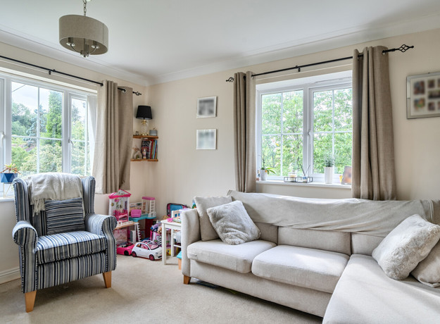Living room with sofa, armchair, window and toys on shelves.