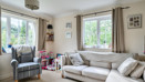 Living room with sofa, armchair, window and toys on shelves.