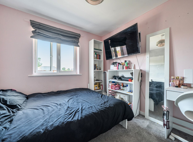Bedroom with a double bed, shelving unit, desk and wall-mounted television.