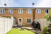 Rear garden with a lawn, patio area and terraced house beyond.