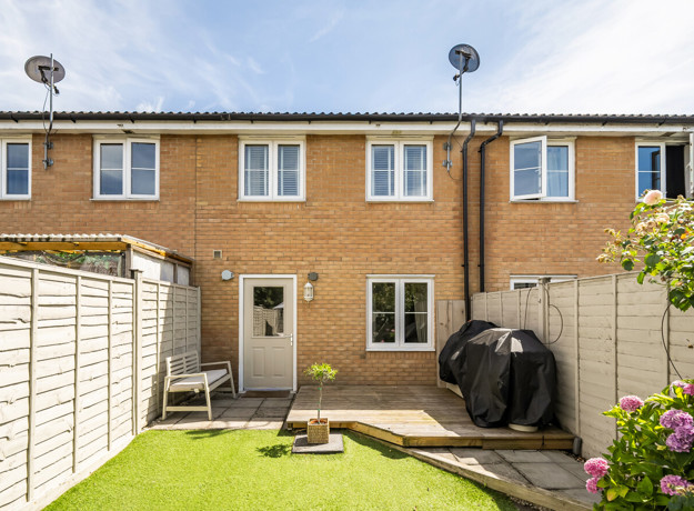 Rear garden with a lawn, patio area and terraced house beyond.