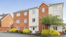 Modern red brick apartment building with white trim and small landscaped shrubs.