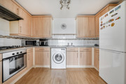 Kitchen with cabinets, oven, washing machine, and refrigerator.