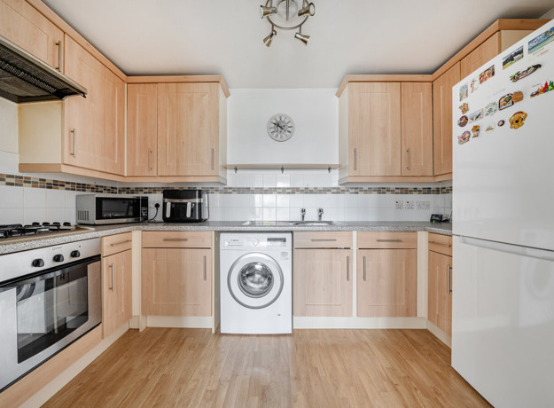 Kitchen with cabinets, oven, washing machine, and refrigerator.