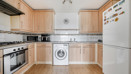 Kitchen with cabinets, oven, washing machine, and refrigerator.