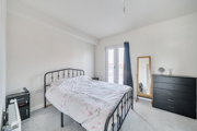 Bedroom with metal bed frame, chest of drawers and freestanding mirror.