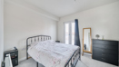 Bedroom with metal bed frame, chest of drawers and freestanding mirror.