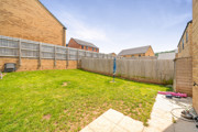 Enclosed rear garden with lawn, fences, and neighboring houses.
