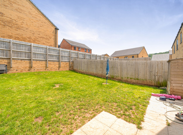Enclosed rear garden with lawn, fences, and neighboring houses.