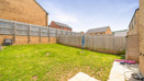 Enclosed rear garden with lawn, fences, and neighboring houses.